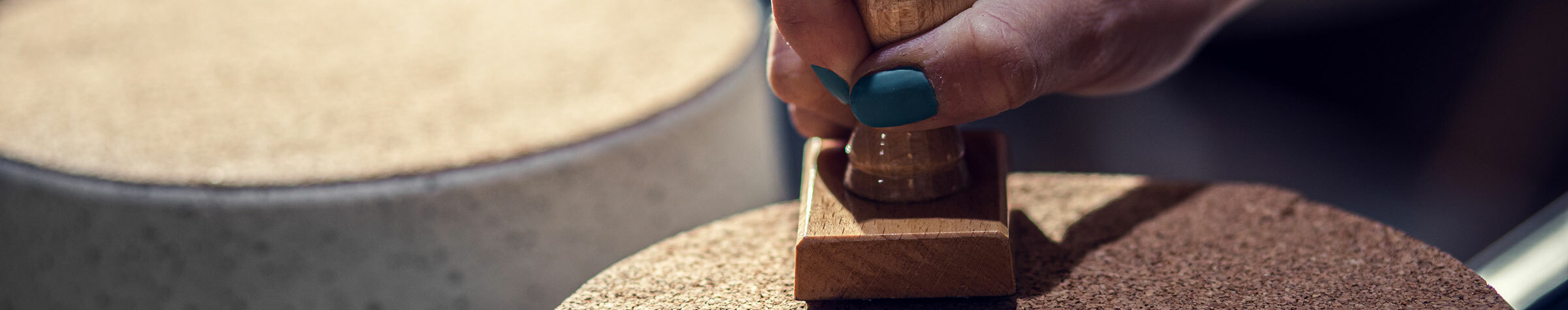 Close up of craftswoman hands stamps trademark on her product