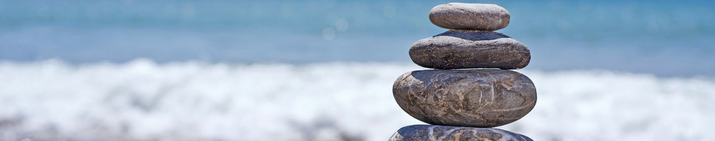 Several stone stacked on top of each other in front of a body of water