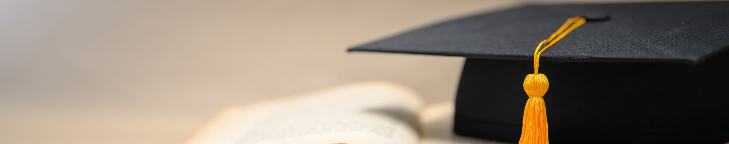 Black graduation cap with a gold tassel sitting on a book