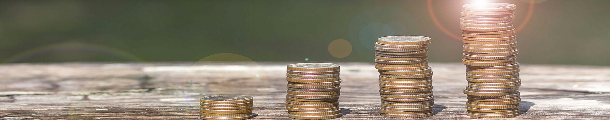 Four stacks of coins on a wooden surface