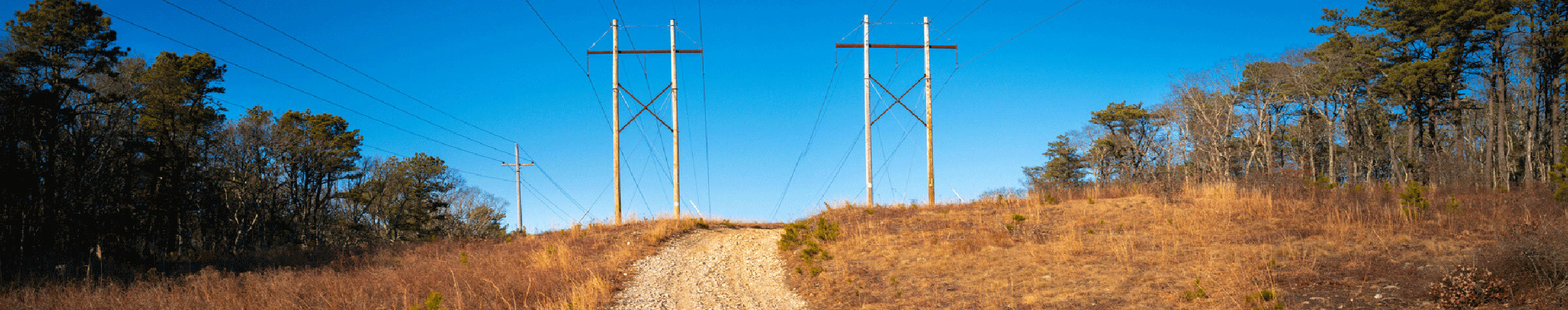 Dirt road between two powerlines in a rural area